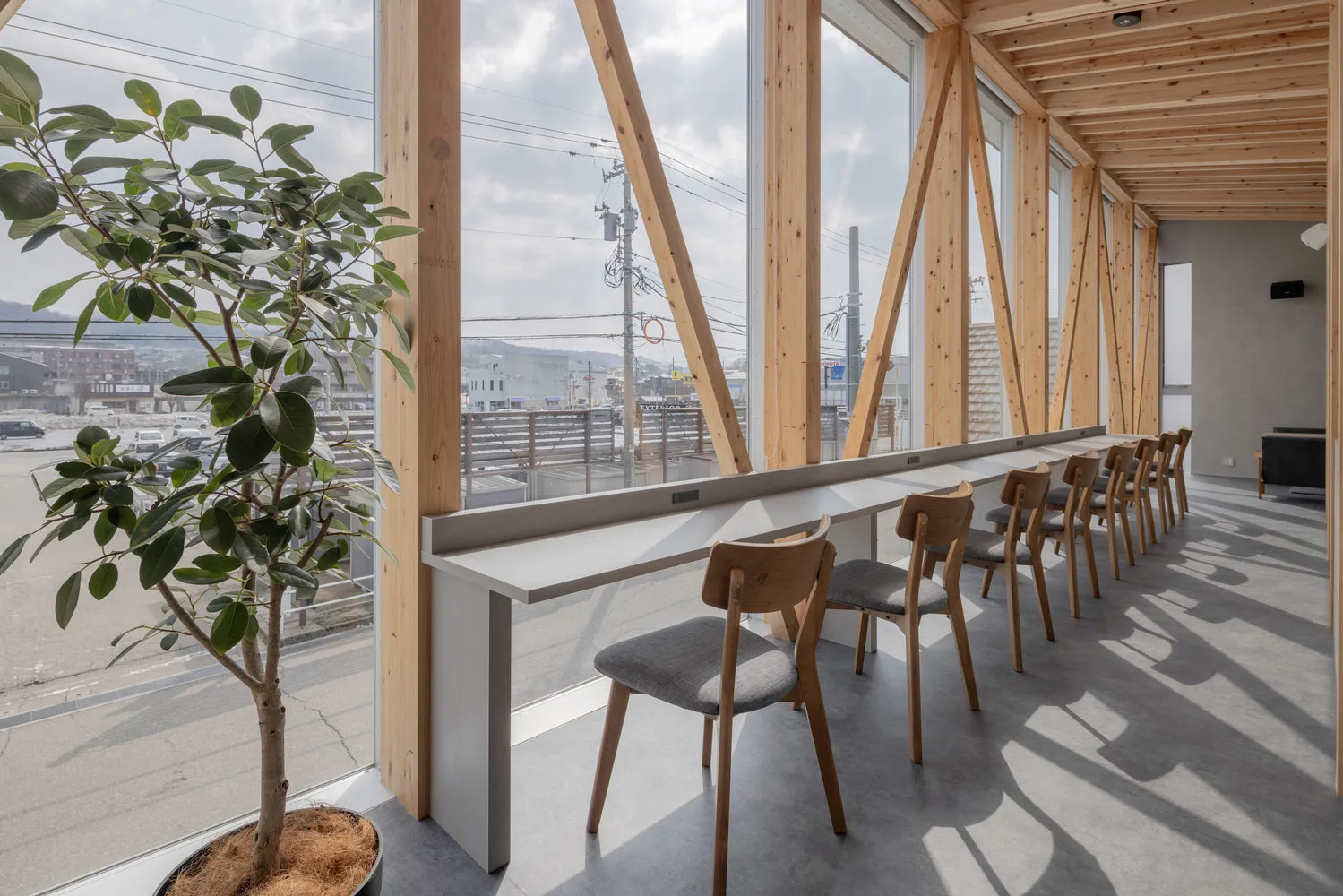 Open modern living space with wooden elements, a large window, and natural light from the window