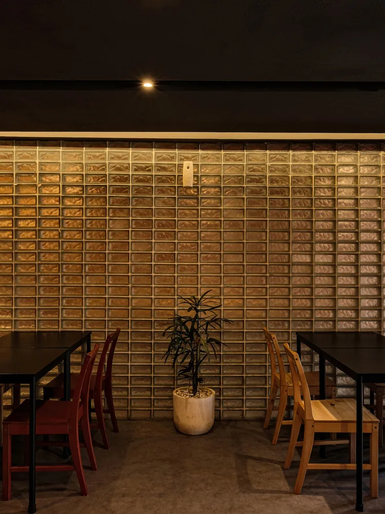 Dining area with tables and chairs, tile walls, a potted plant, and modern decor