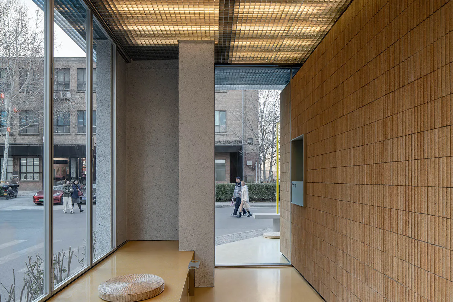 Bright and inviting hotel lobby with a yellow bench, guests walking by, and a welcoming atmosphere