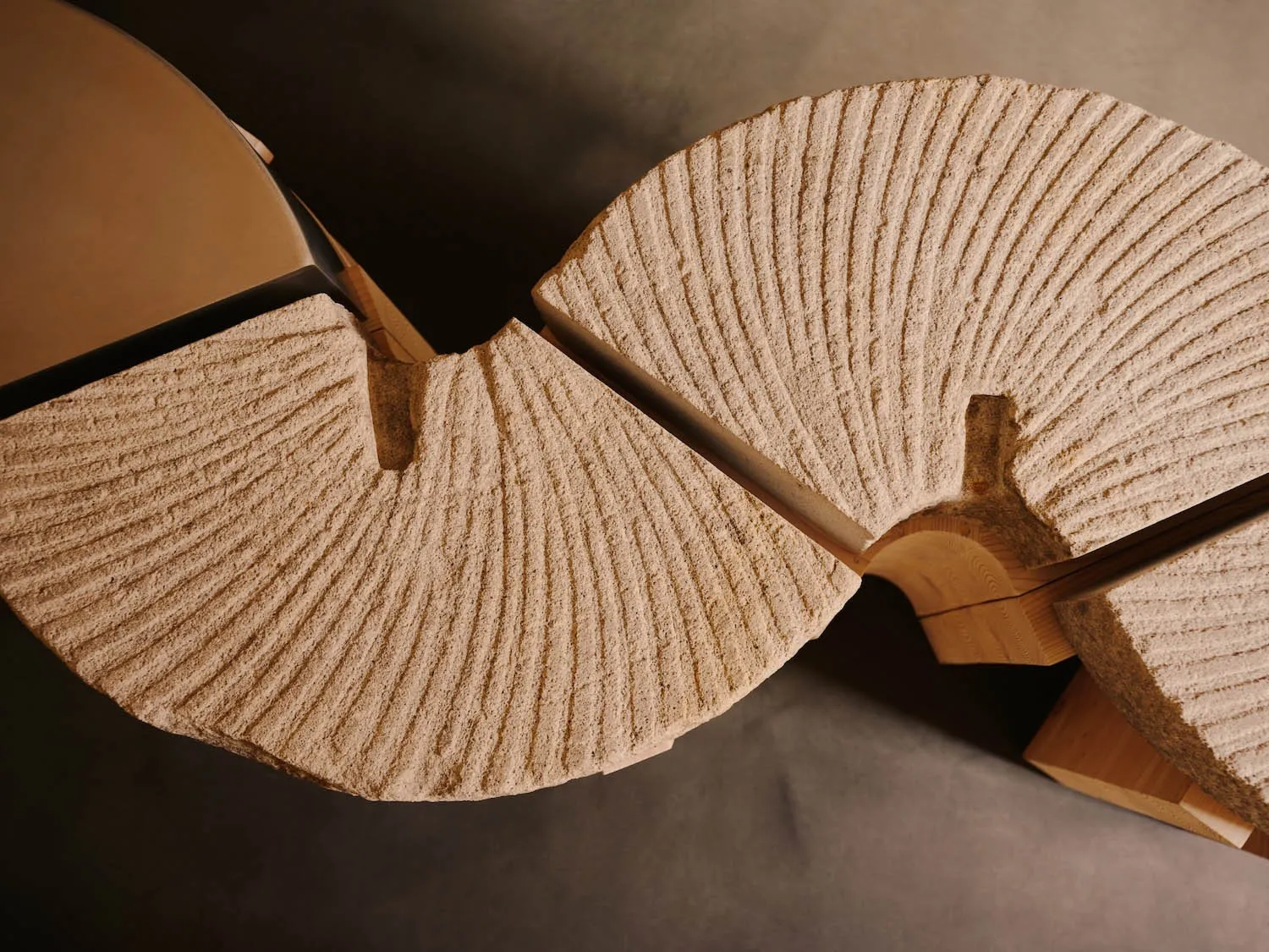 A minimalist wooden chair with a unique shape, set against a neutral background, with dramatic lighting creating depth and contrast