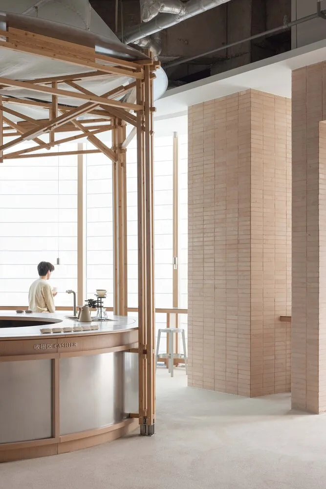 A restaurant interior with a wooden theme, featuring a metal countertop, sink, and coffee maker, with two people in the scene