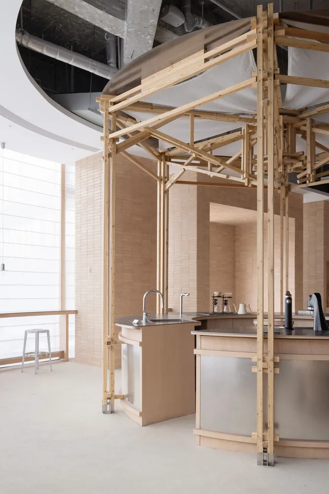 A kitchen area with a sink under a wooden structure, two bottles near the sink, and a functional yet stylish atmosphere