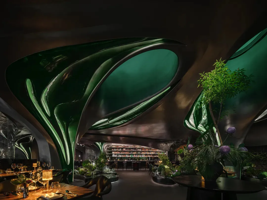 A modern restaurant with green and purple tile walls, potted plants, and a comfortable atmosphere