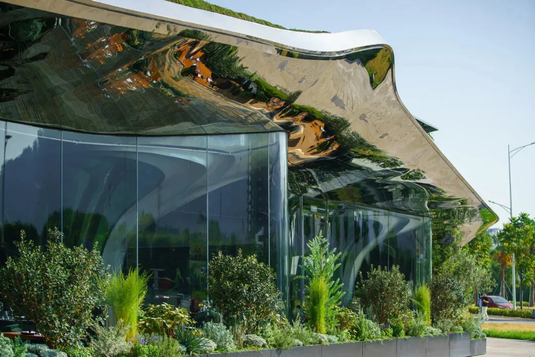 Modern building with glass walls, natural light, and potted plants, featuring a minimalist design with clean lines and simple shapes