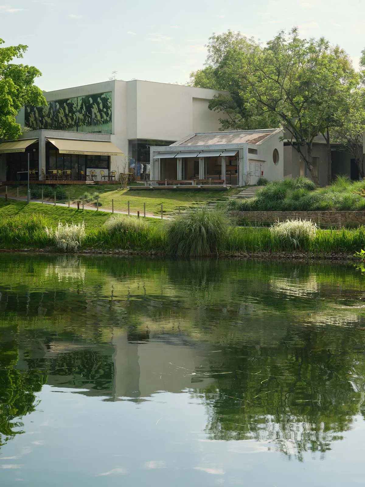 A restaurant with a patio area featuring dining tables, chairs, and umbrellas, situated next to a body of water