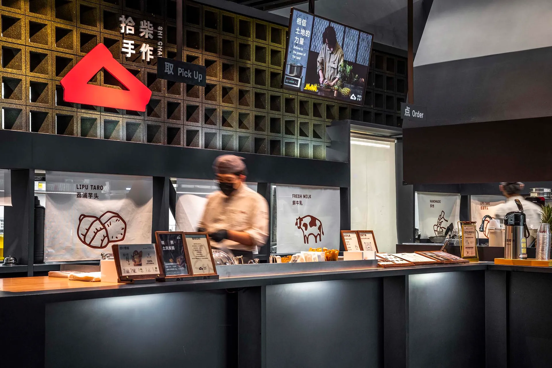 休閒亞洲餐廳，吧台展示美食，牆上掛電視，場景中有兩人