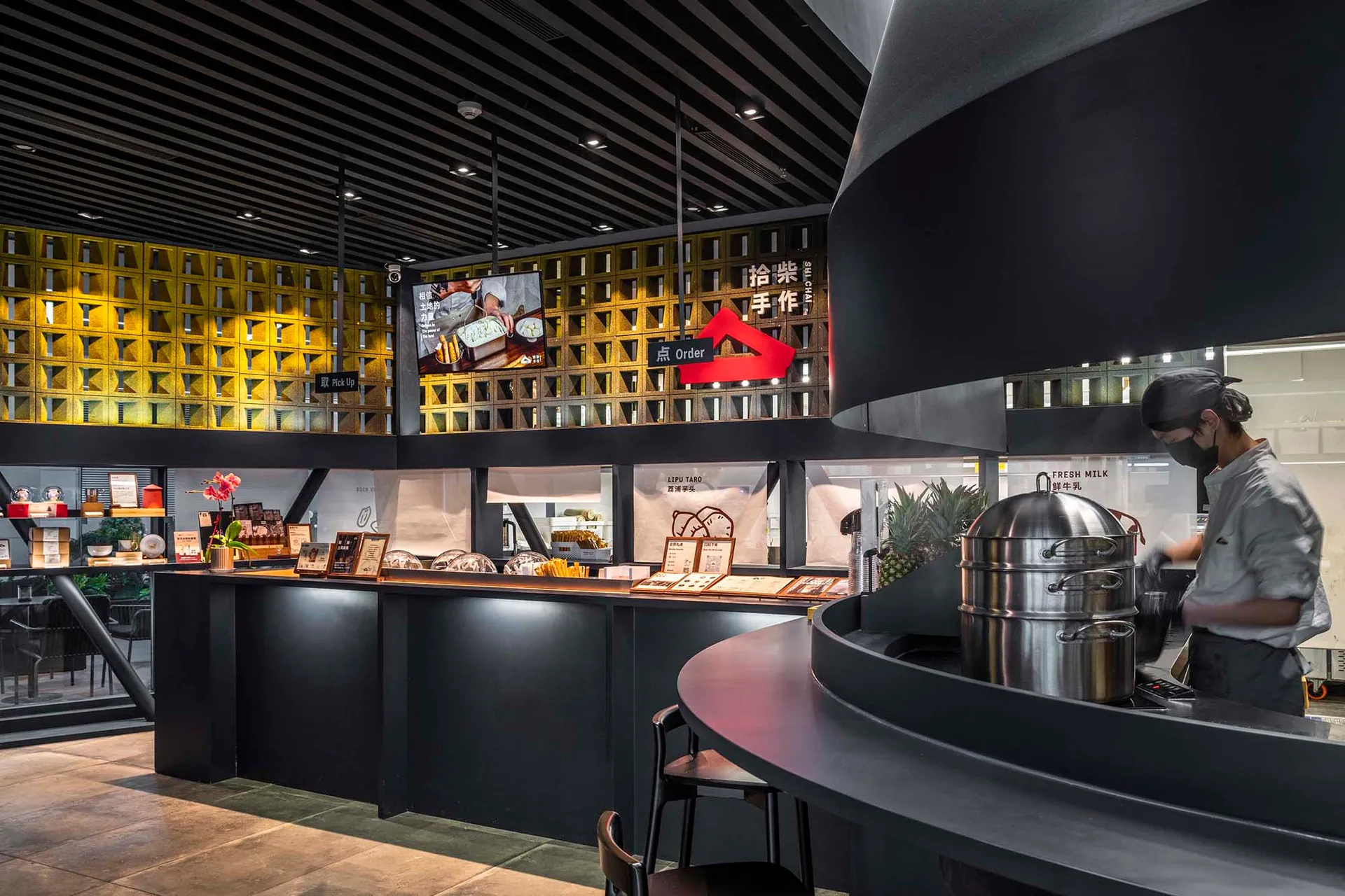 Modern restaurant interior with a black countertop, yellow accents, and seating for customers