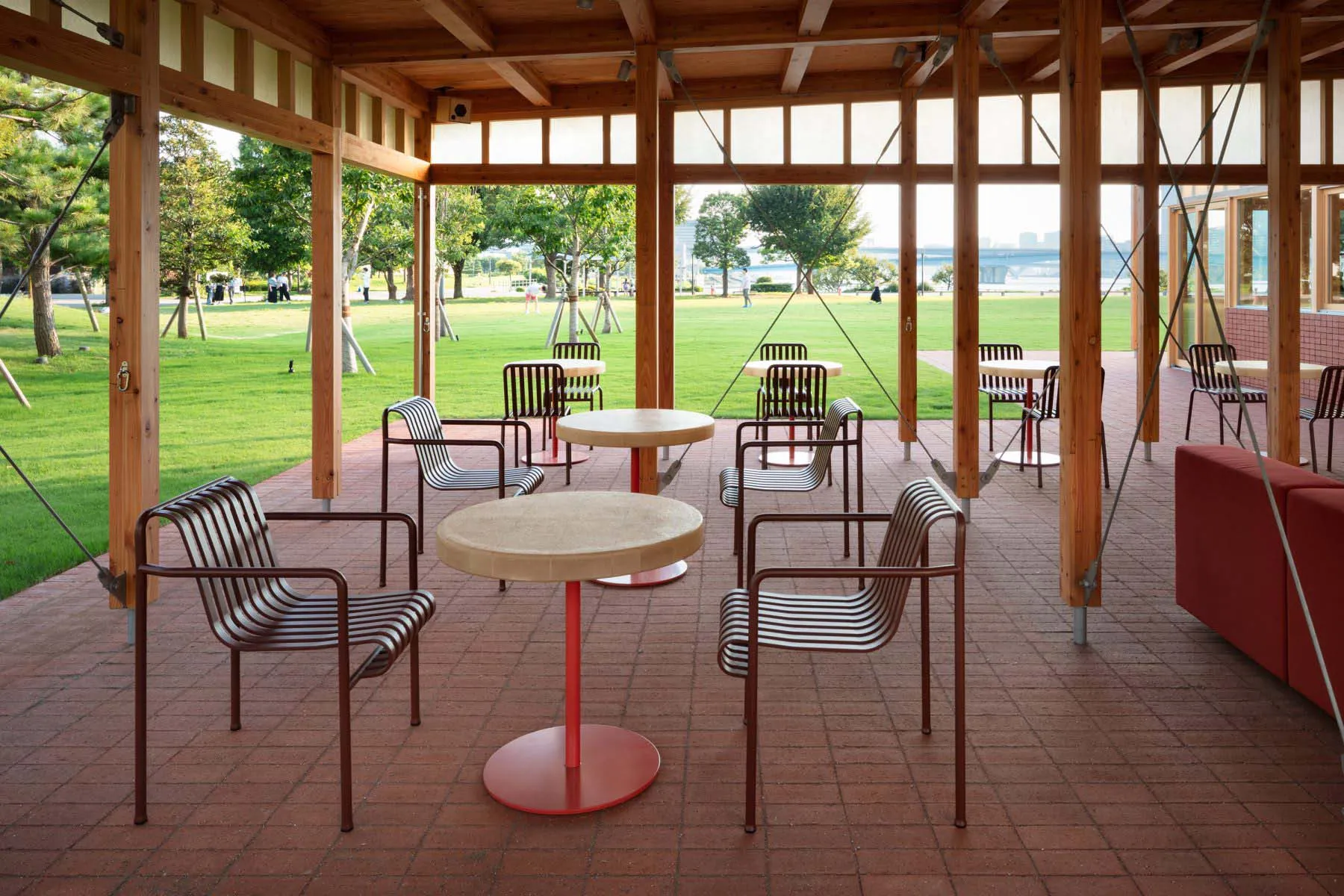 A round wooden dining table surrounded by several chairs in a comfortable outdoor patio setting