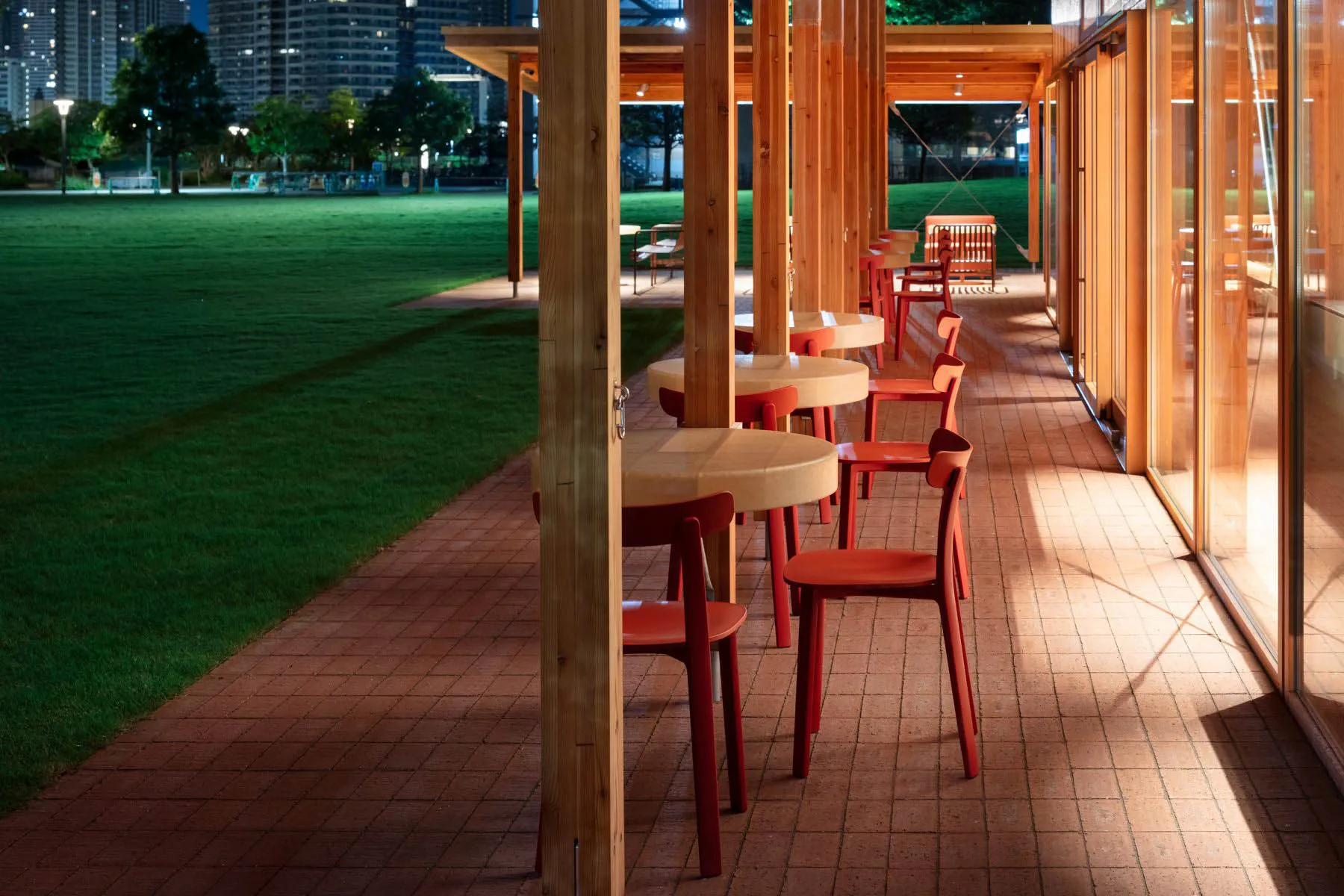 A restaurant or café outdoor dining area with multiple wooden tables and chairs, creating a comfortable seating arrangement for guests