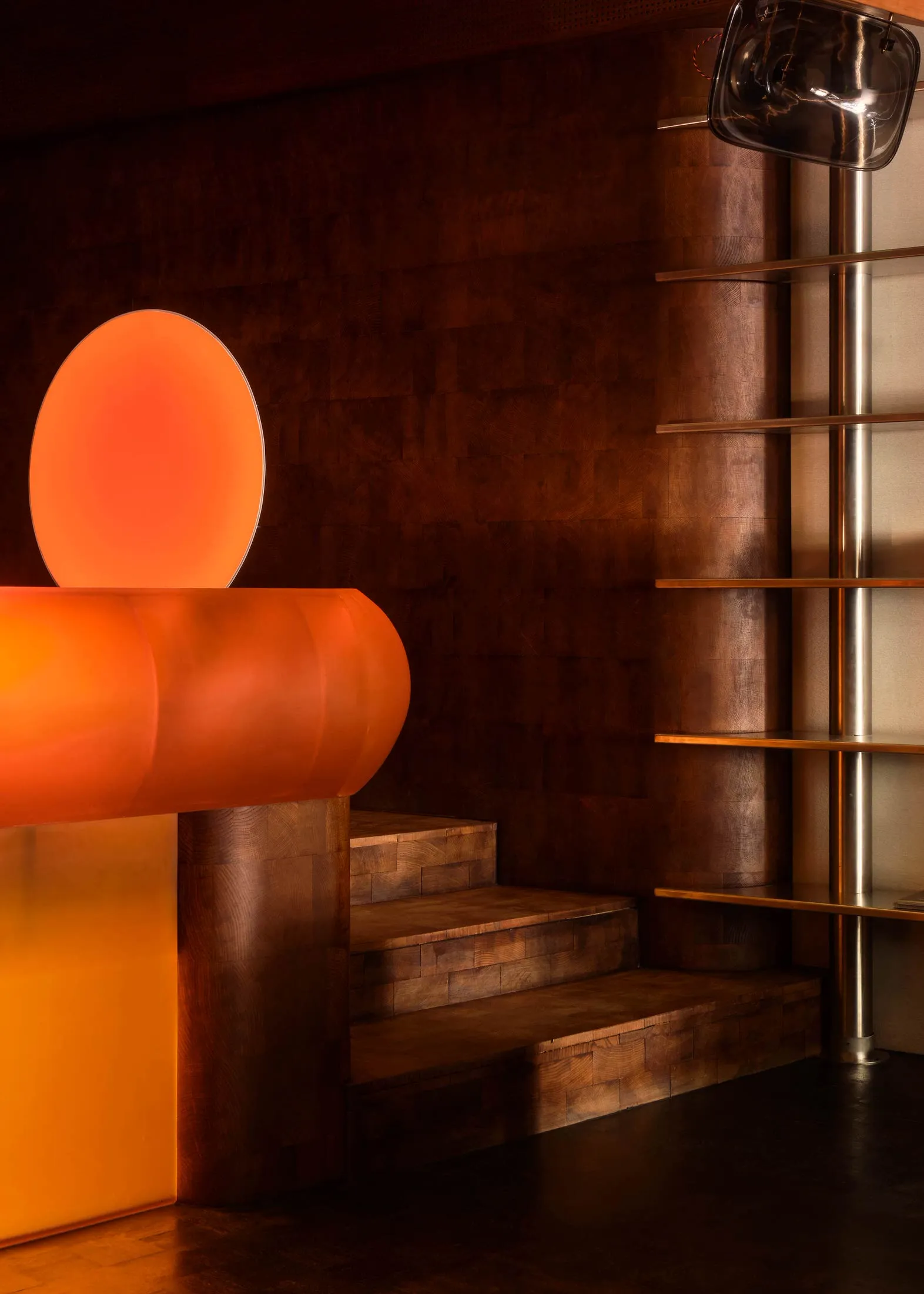 A warm and inviting interior space with a wooden and metal staircase, a large orange circle on the wall, and a cozy atmosphere