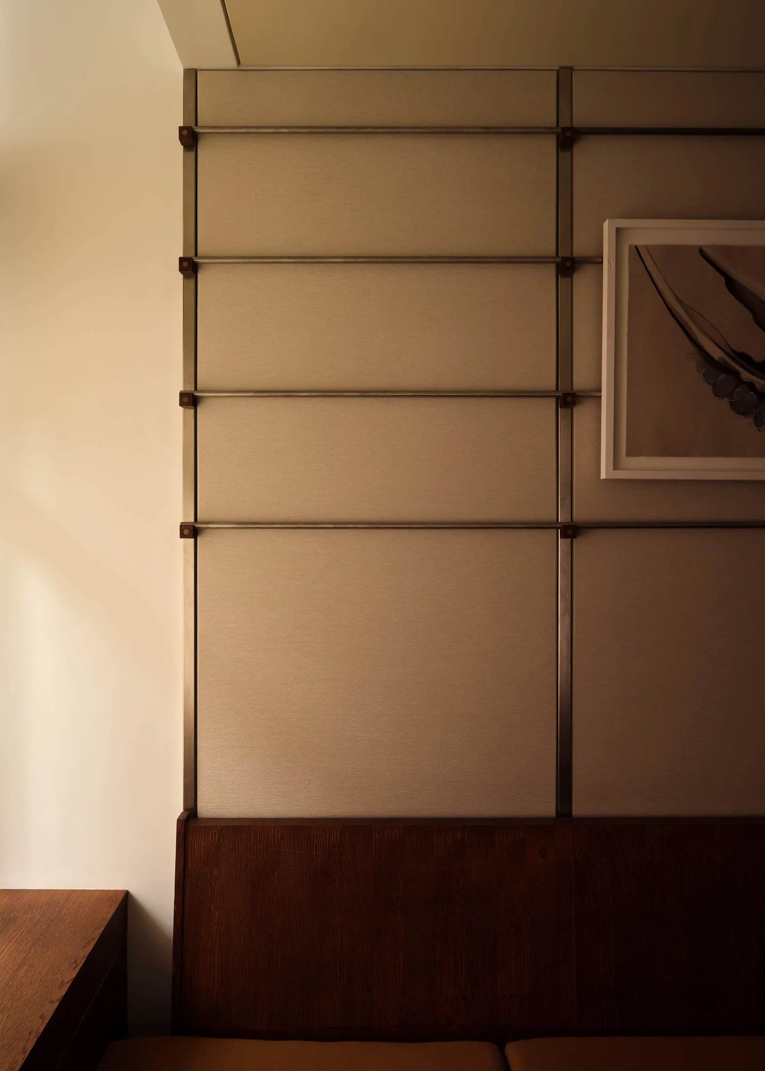 A wooden wall with a metal frame and two pictures, in a cozy and warm interior space