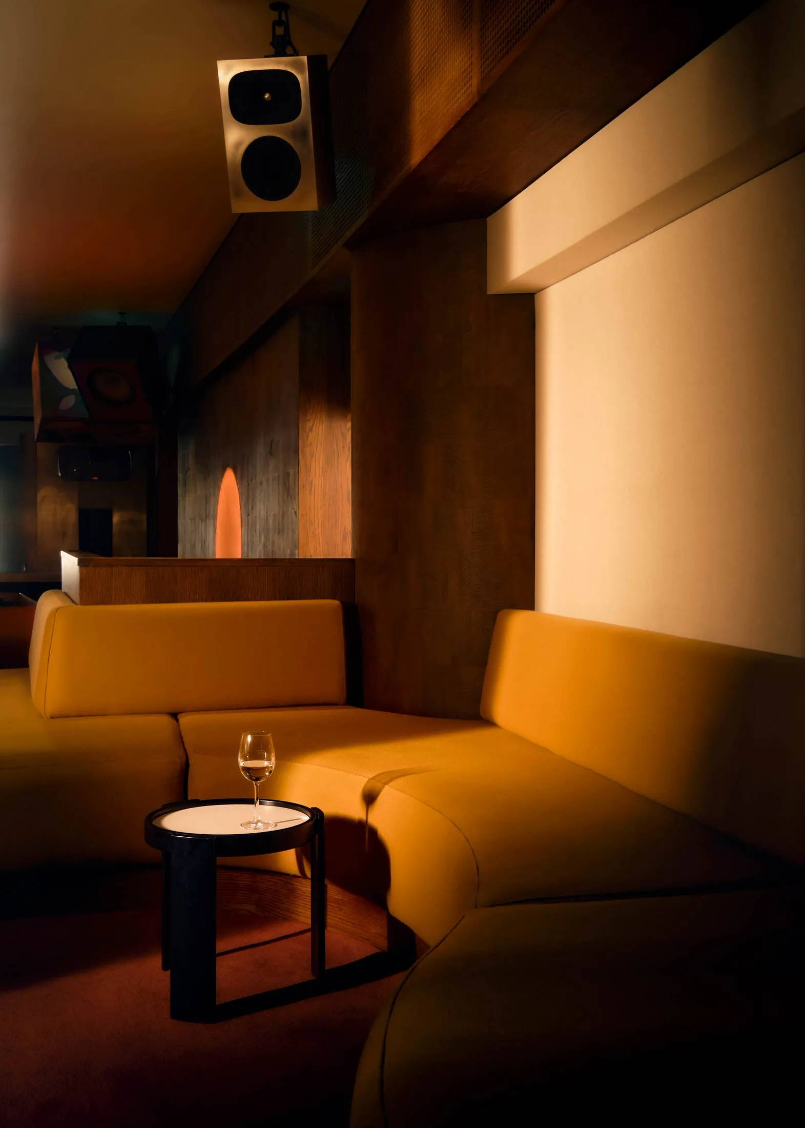 Cozy living space with a yellow couch, brown chair, and a dining table surrounded by seating arrangements, with a wine glass on the table