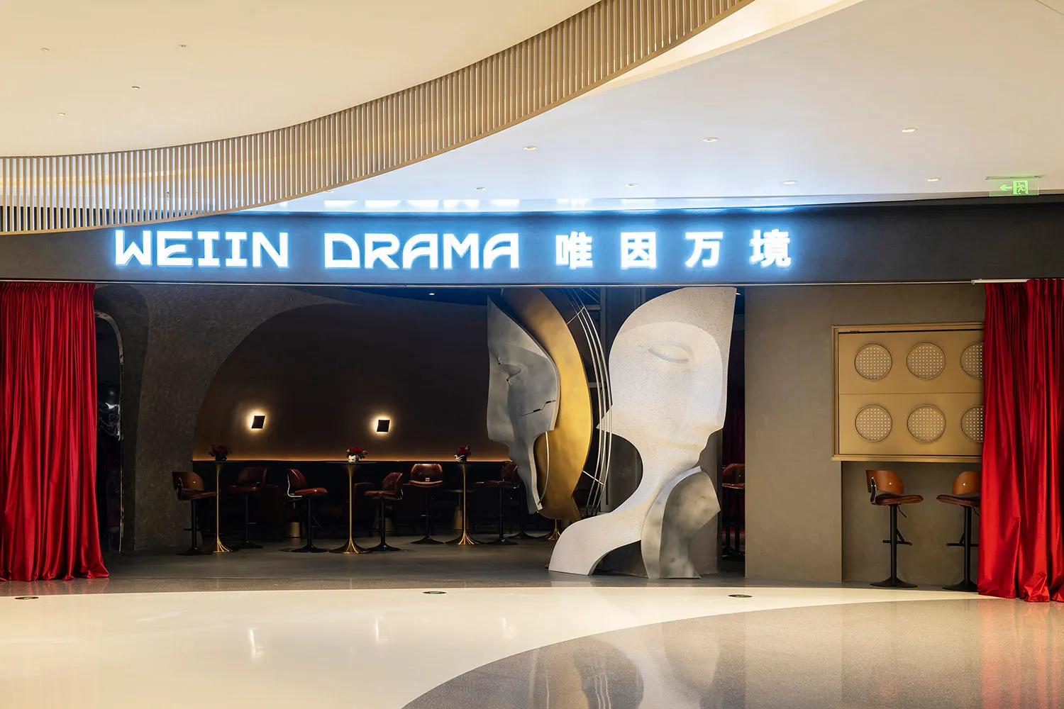 A modern restaurant interior with a central sculpture, chairs, and dining tables, featuring artistic elements and a welcoming atmosphere