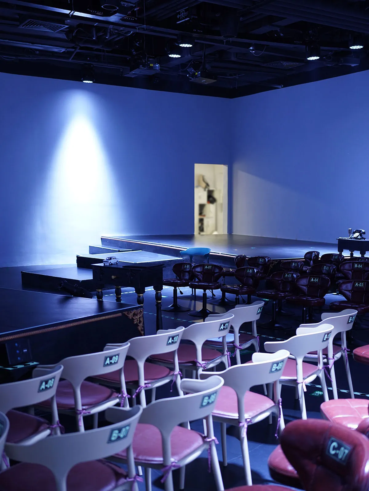 Empty auditorium with rows of wooden chairs arranged on a stage, dimly lit for an intimate ambiance