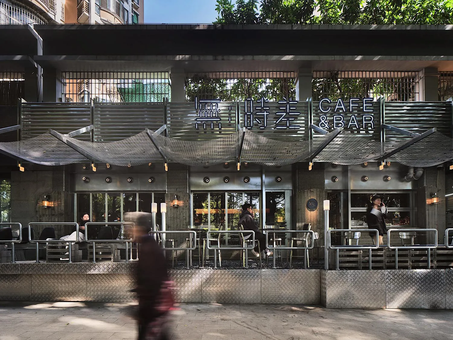 A modern cafe with a dining area, chairs, tables, and potted plants, creating a welcoming atmosphere