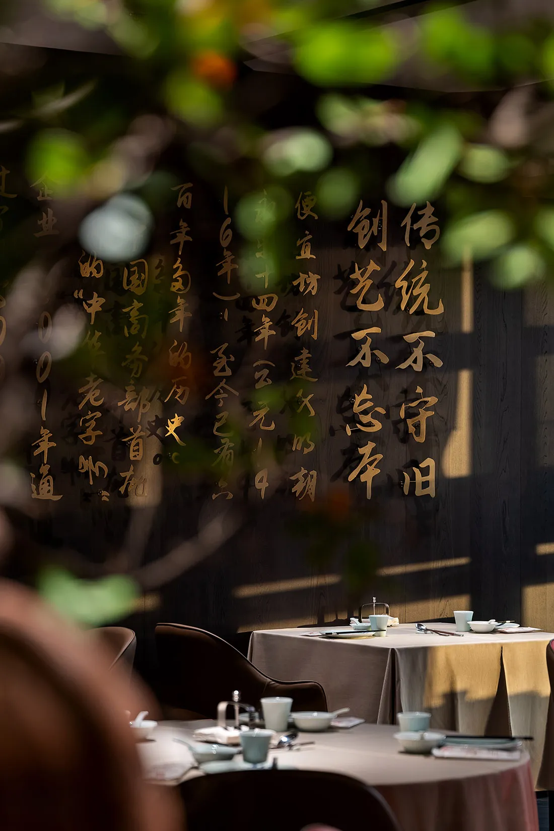 一組餐桌椅，牆上飾有中文書法，周圍擺放杯具，散發溫暖親切的氛圍