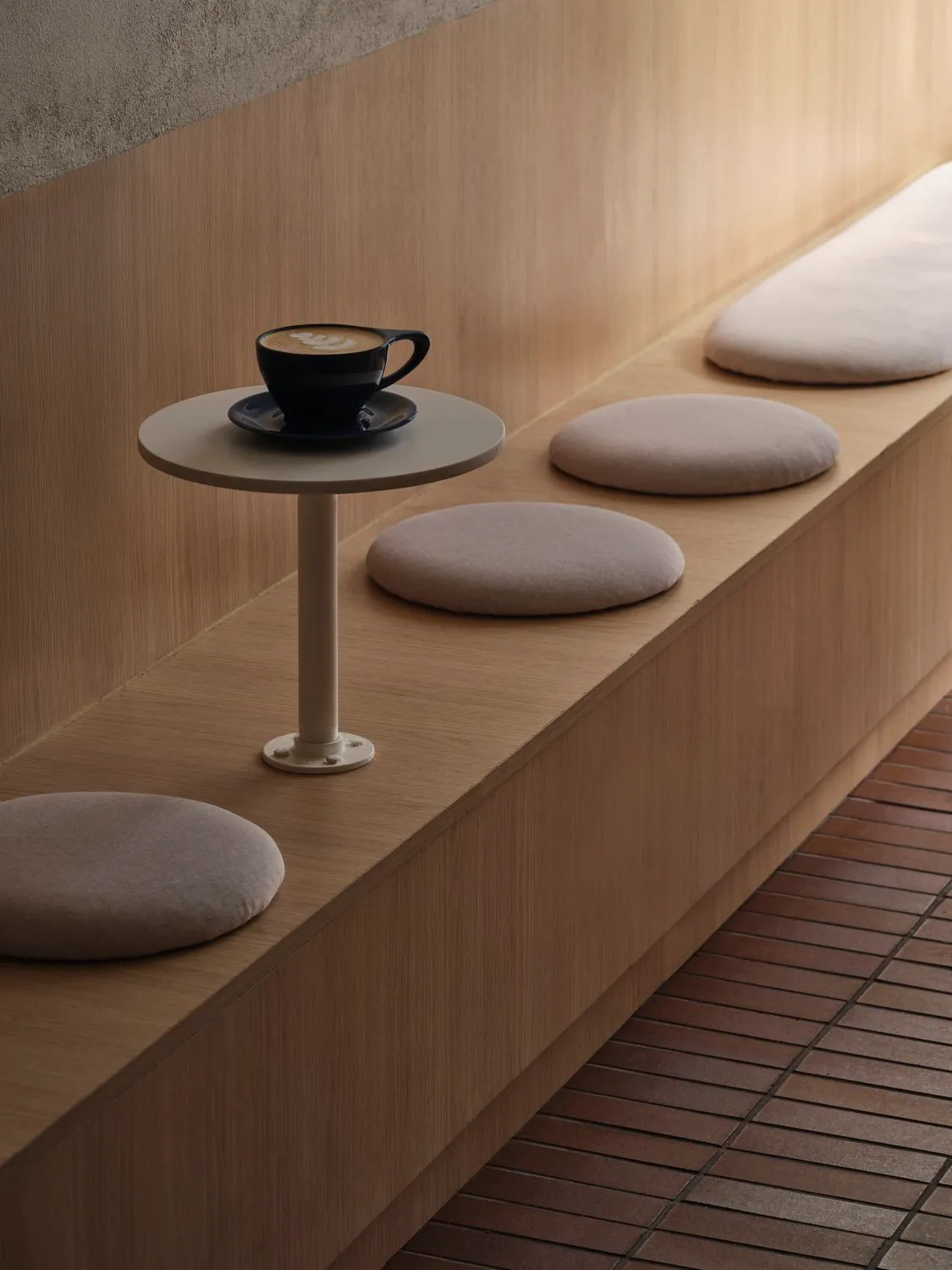 Cozy dining area with a wooden bench and dining table, featuring a cup of coffee on one of the cushions