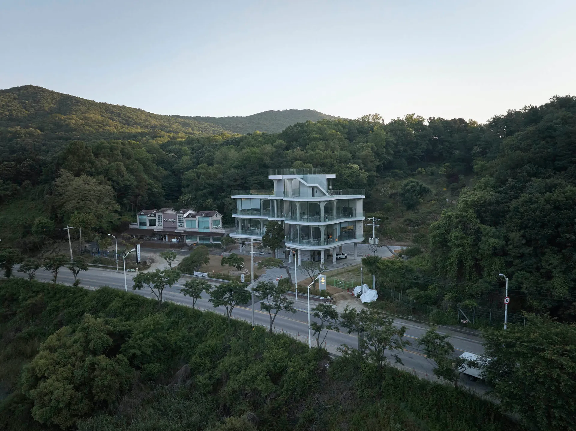 A contemporary building with a concrete exterior, surrounded by trees, featuring a mix of modern and traditional elements, with clean lines and minimalistic design