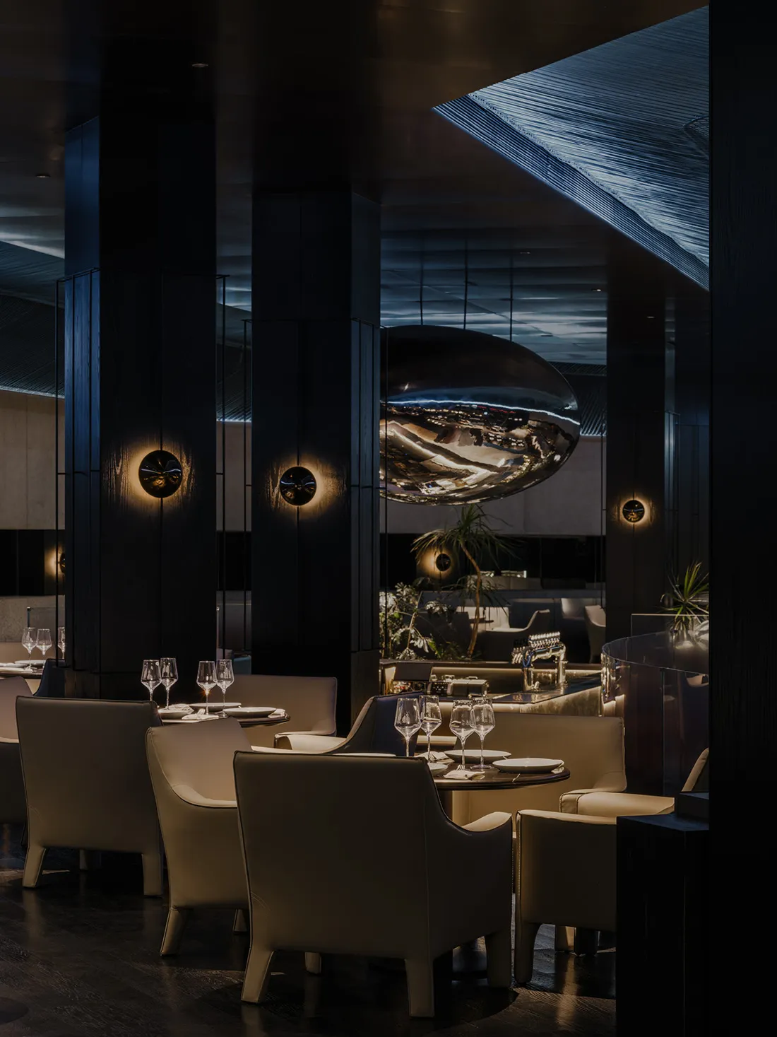 Sophisticated restaurant interior with white furniture, wine glasses, and a large circular centerpiece
