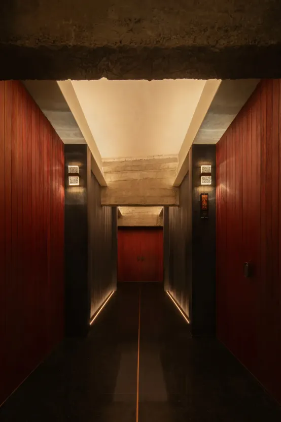 Dimly lit industrial-style hallway with red walls, wooden floors, and two doors on either side