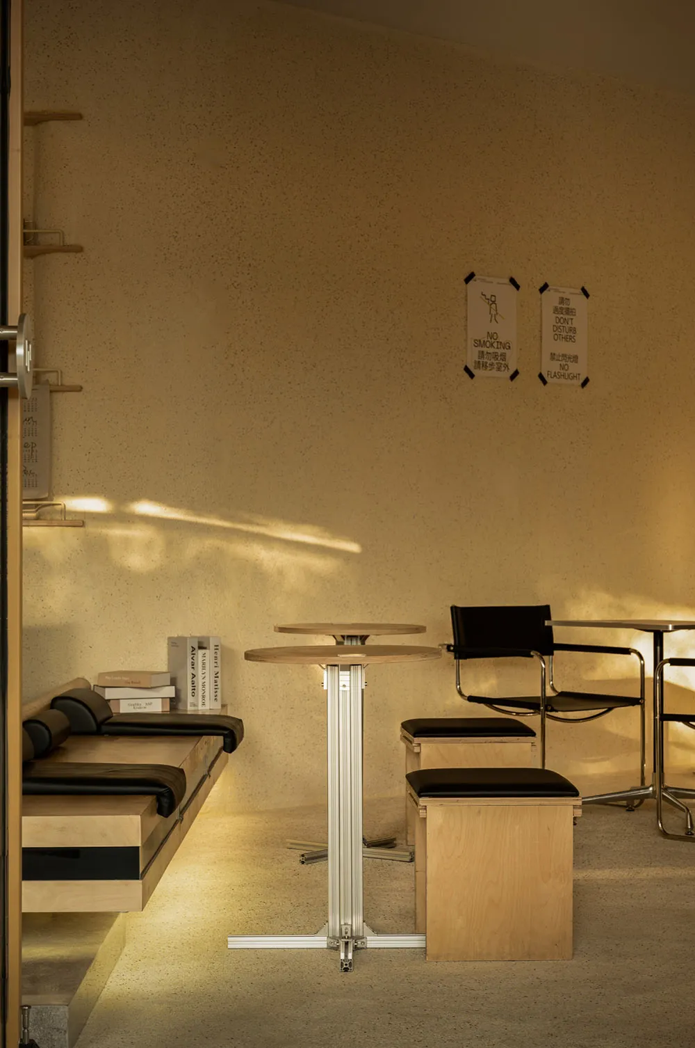 Empty minimalist room with a wooden floor and walls, featuring chairs and a dining table