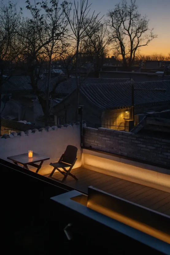 A rooftop dining space with a table, chairs, and a city view in the background, creating a cozy atmosphere with a candle on the table