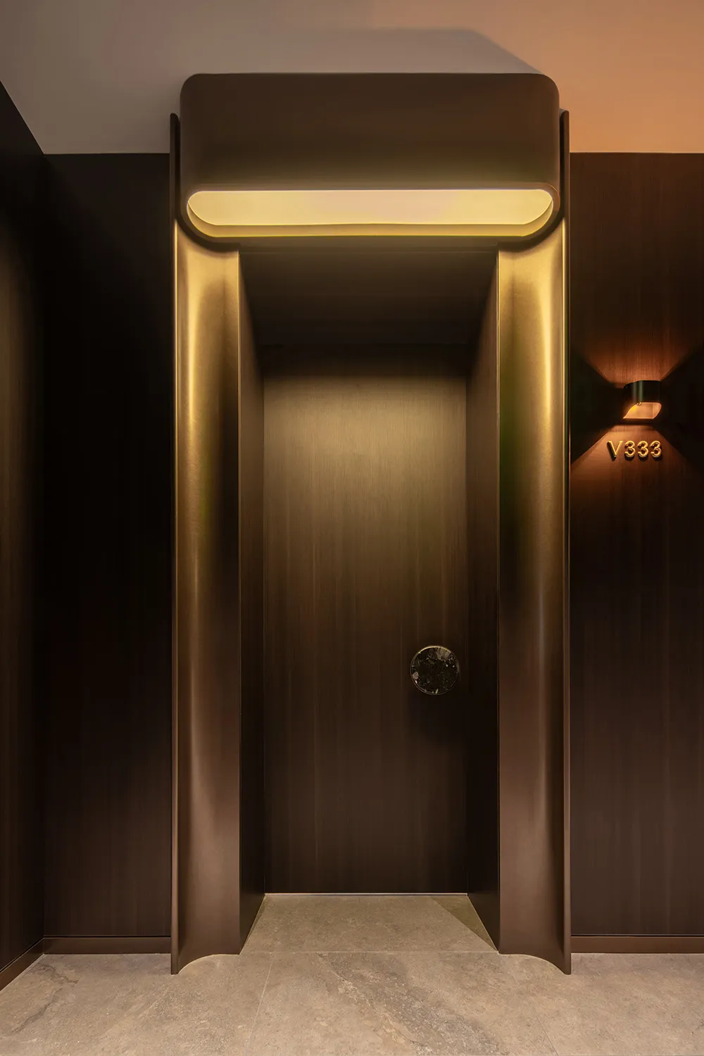 A long wooden hallway with a door on the right side, featuring a gold handle, in a quiet and empty atmosphere