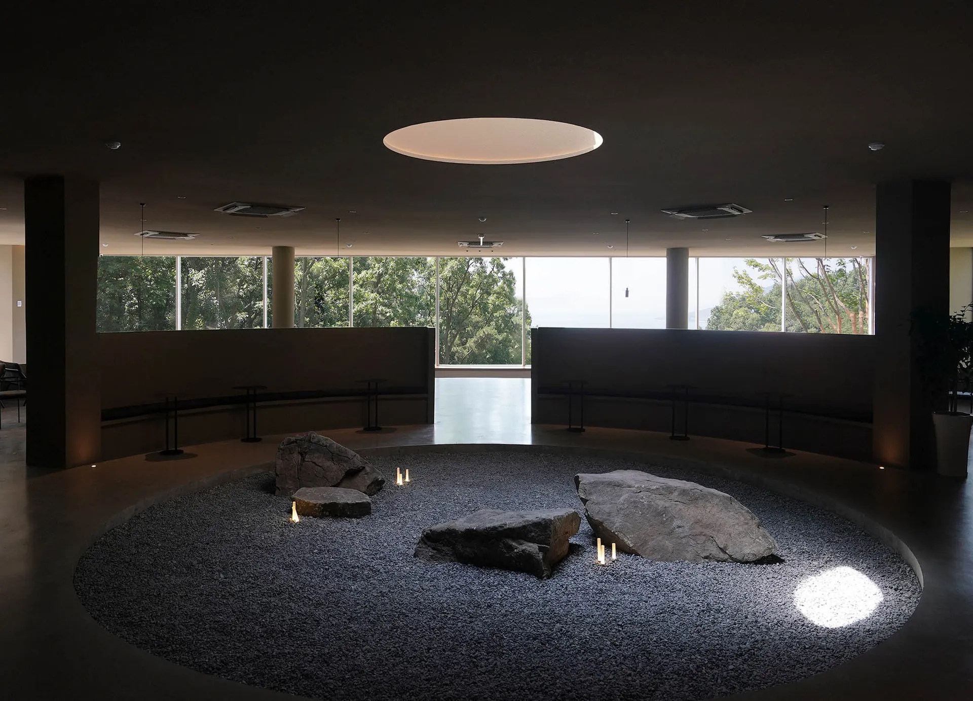A serene indoor space with a large stone circle and benches, encouraging interaction and calmness