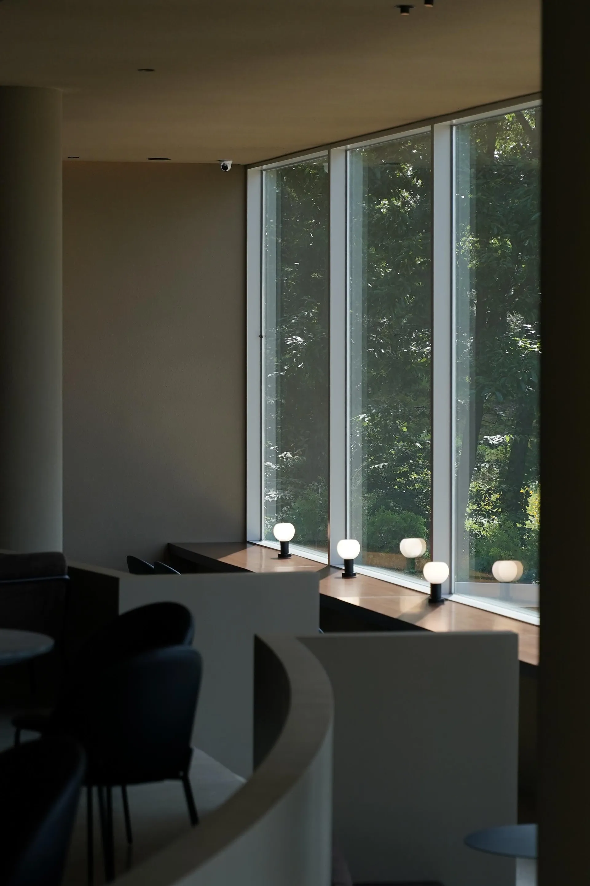 Bright dining room with large windows, two chairs, and three dining tables, with a warm and inviting atmosphere
