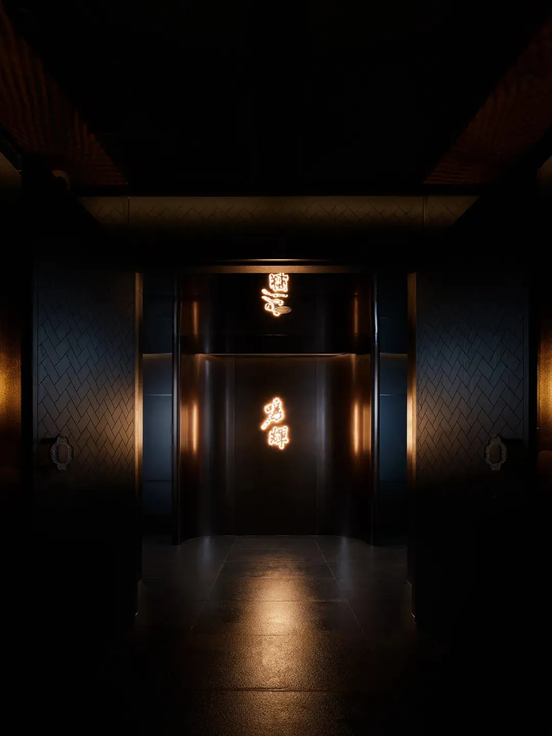 A darkened elevator with a glass door and oriental writing on the walls, lit by a warm yellow glow