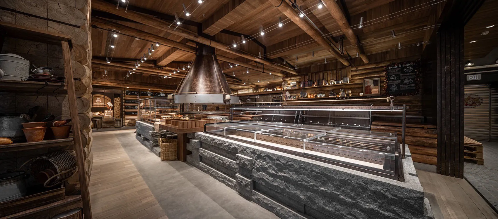 Warm and inviting restaurant interior with a large stone wall, brick oven, and comfortable seating areas