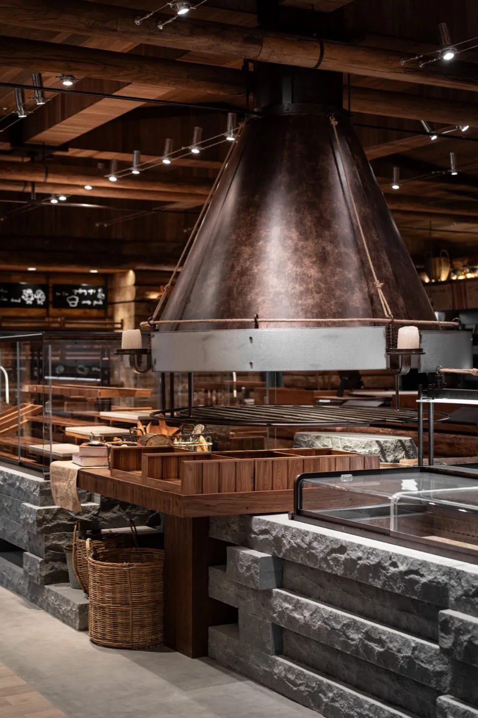 Cozy restaurant dining area with a large stone oven, wooden elements, and stone walls, featuring a central fireplace