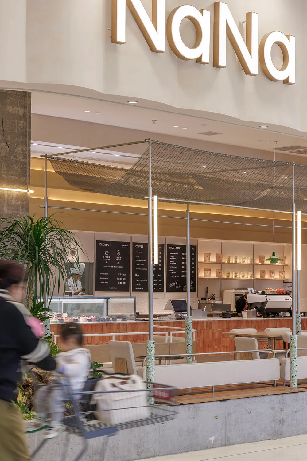 Modern cafe and restaurant interior with wooden floors, white walls, chairs, dining tables, and a potted plant