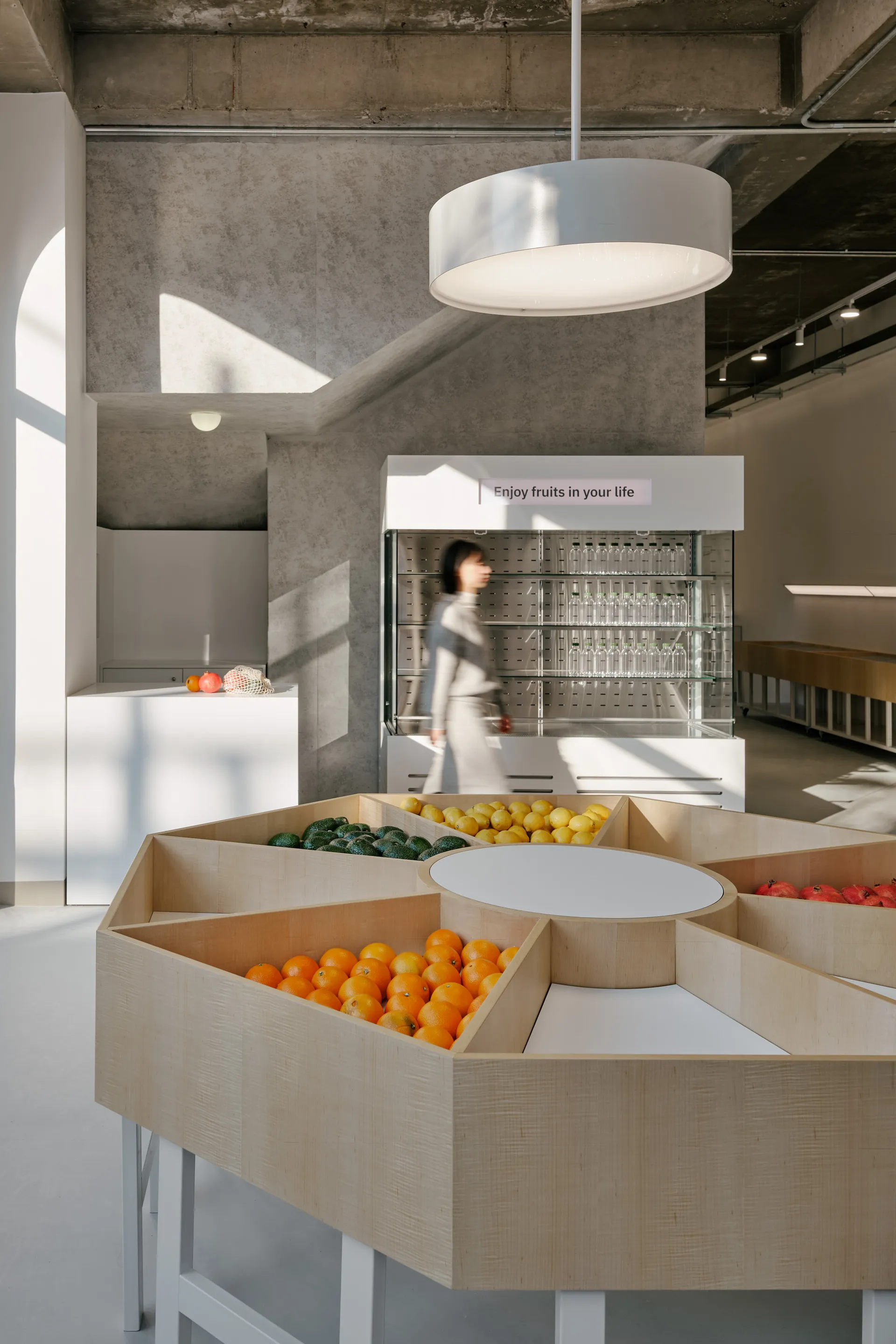 A bright and inviting store filled with bowls of fresh fruit and vegetables, with a woman browsing the selection