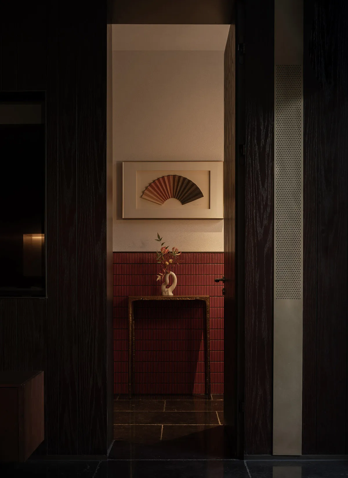 Warm and inviting room with a red brick wall, wooden doorway, vases, and a potted plant