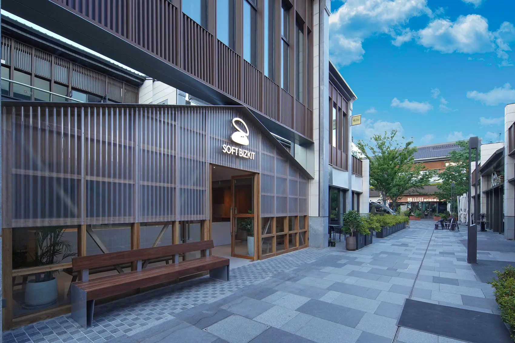 A wooden building with a large window and two wooden benches in front, set in a calm and inviting environment