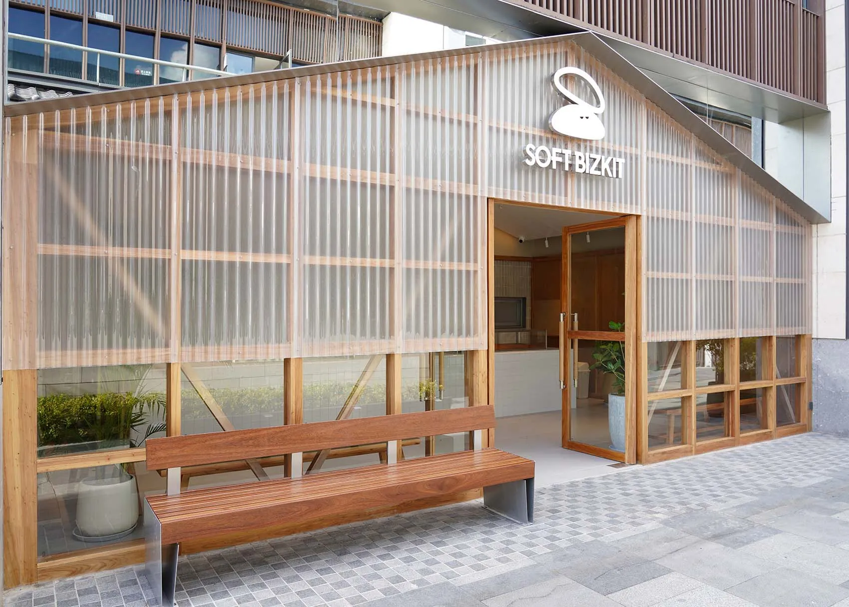 開放式客廳區域配有木製長椅、玻璃門、盆栽植物與水槽，營造溫暖親切的氛圍，融入自然元素