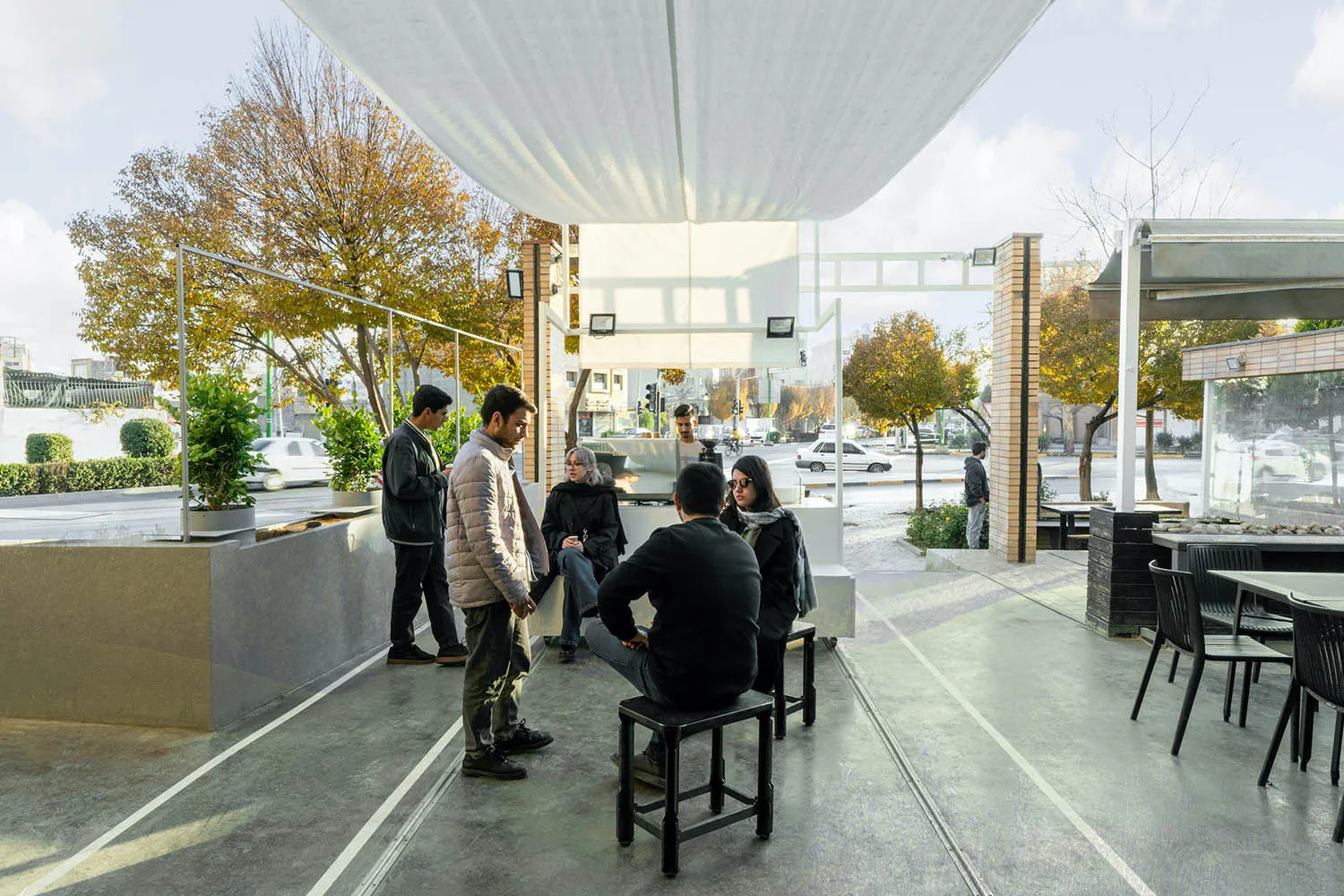 A casual dining space with a mix of wood and metal elements, featuring multiple tables and chairs, and a social atmosphere