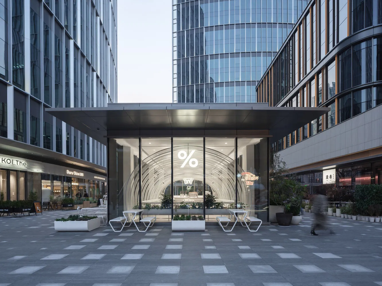 Modern restaurant with glass walls, tables, chairs, and a covered area with a prominent archway