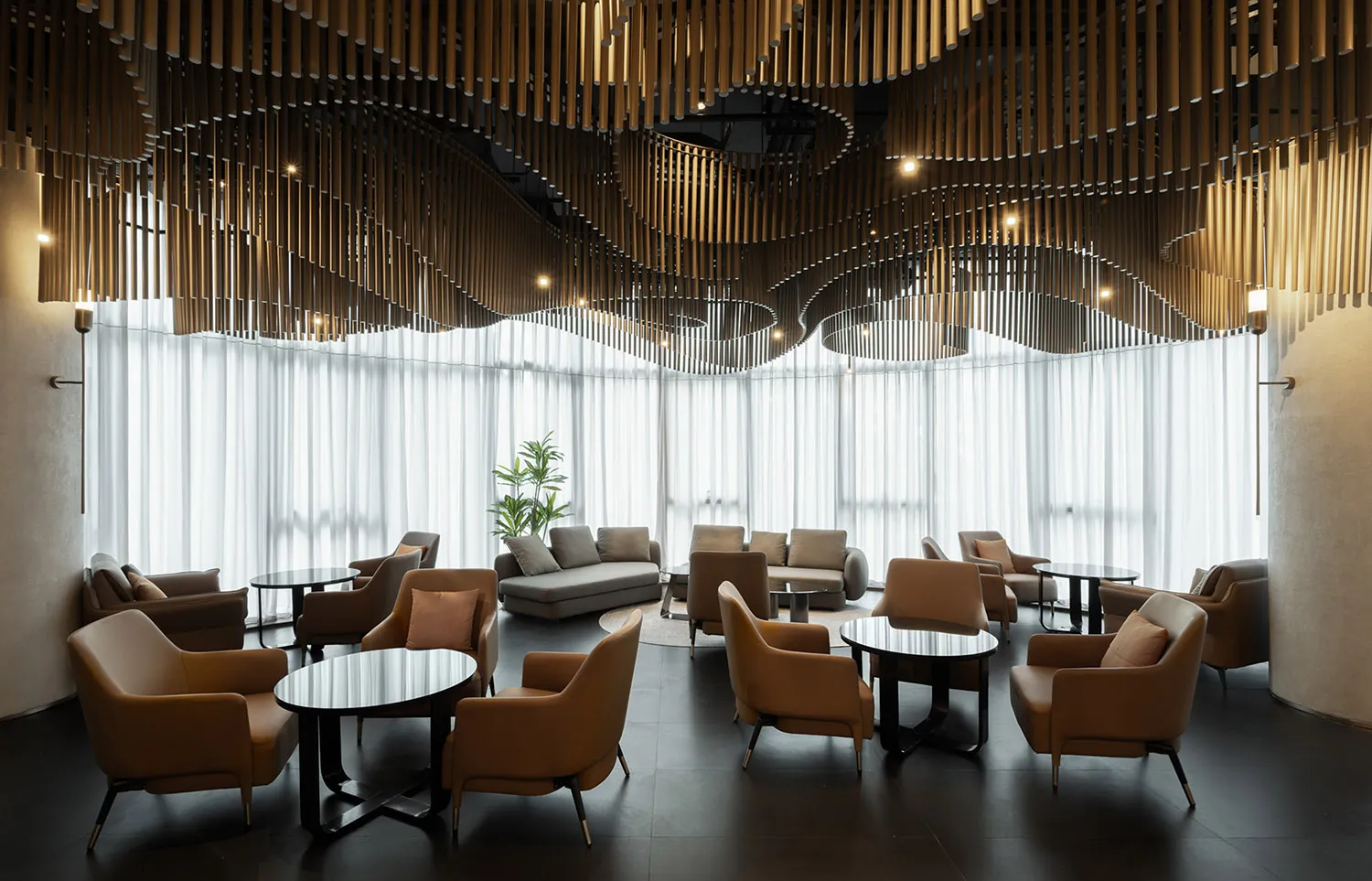 A well-lit interior design featuring multiple seating areas, dining tables, and natural light from windows, creating an inviting atmosphere for social gatherings or relaxation