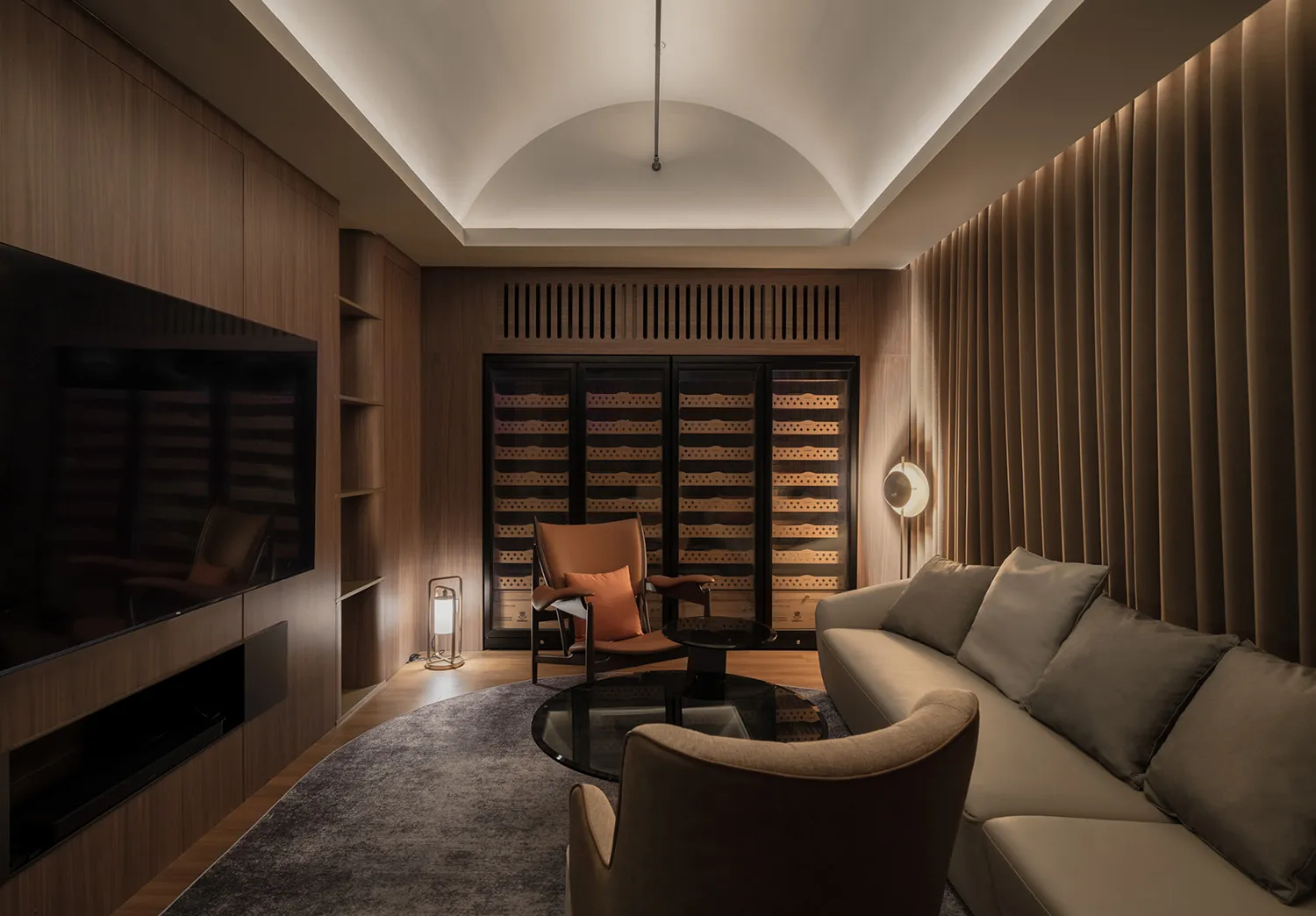 A well-lit living room with a modern design, featuring a couch, chairs, and wine glasses on surfaces