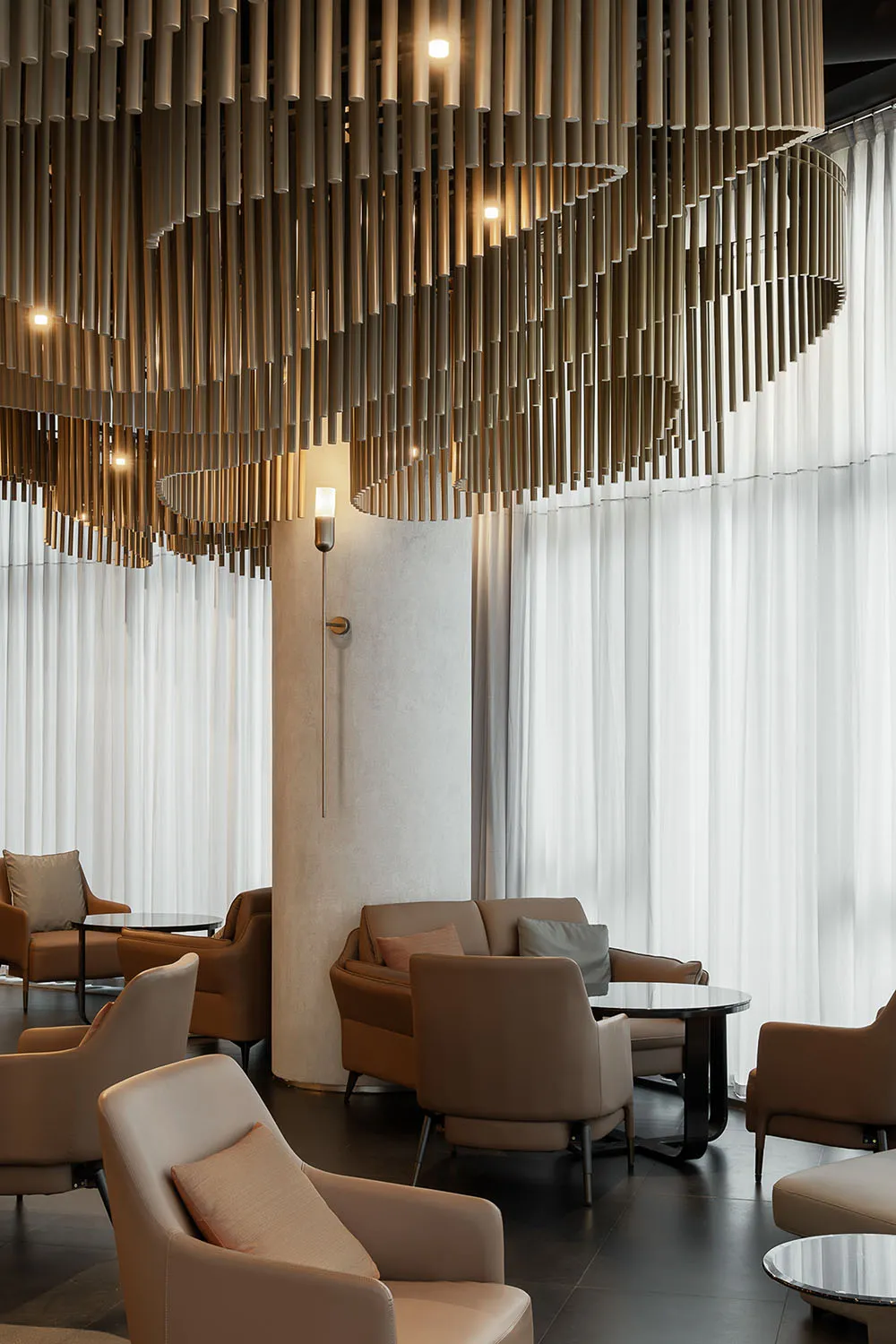 A modern living space with three couches, two chairs, and three dining tables, featuring leather and wood furniture, white walls, and soft warm lighting