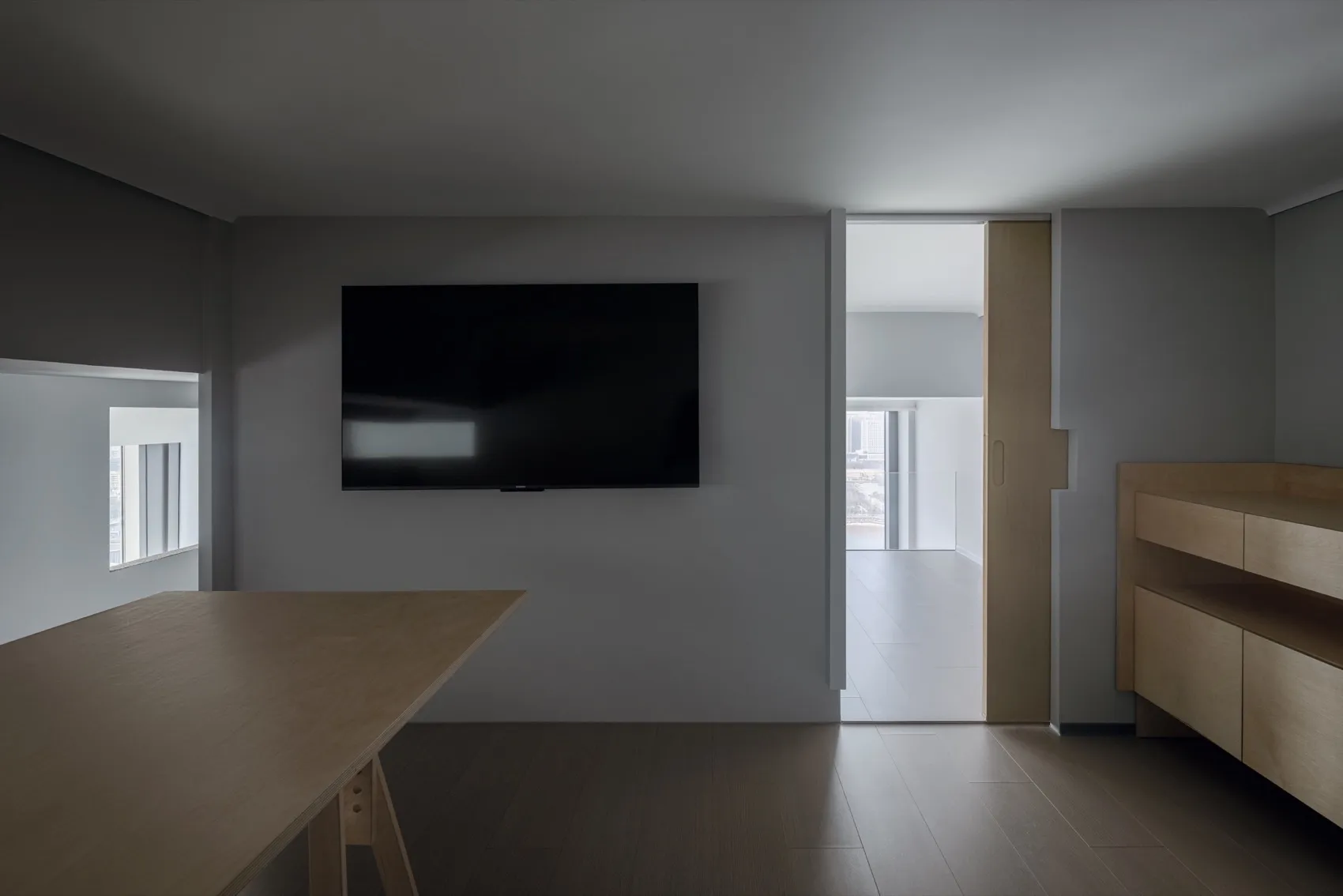 Empty living room with a flat screen TV, wooden floors, and good lighting