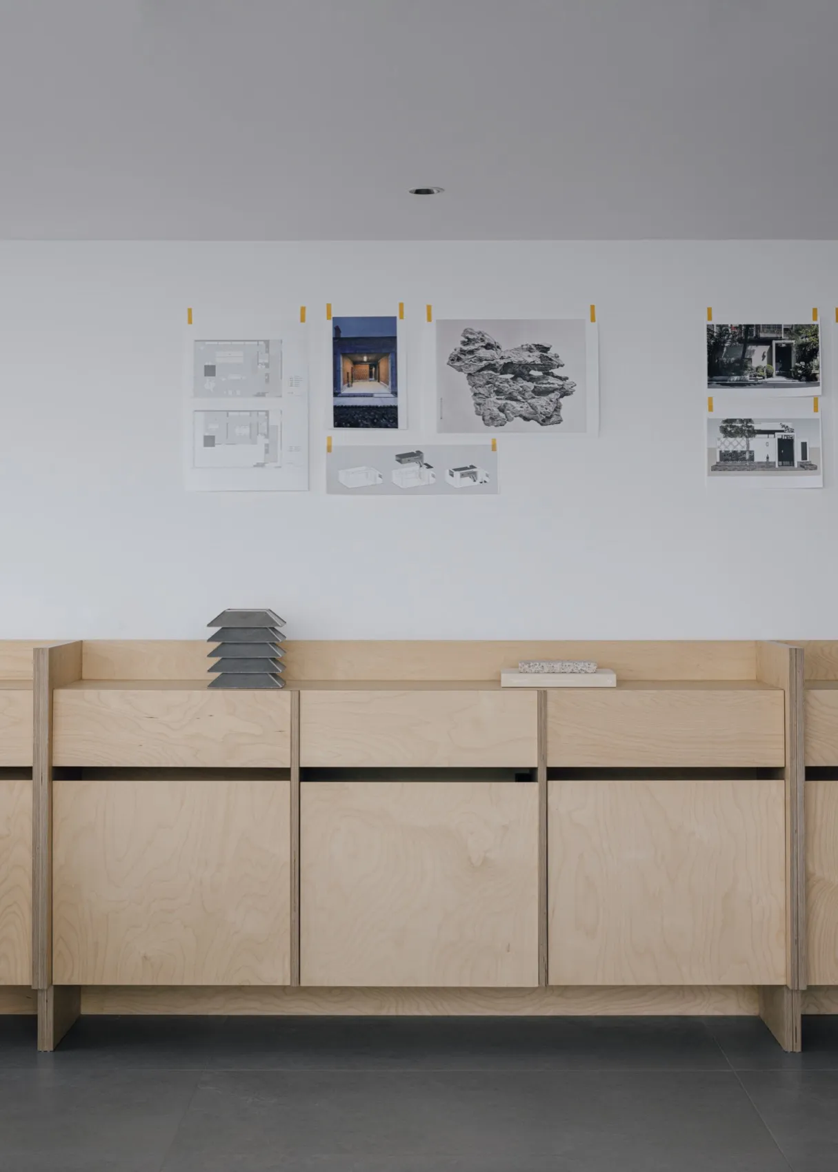 A professional office space with pinned architectural plans and books on the wall