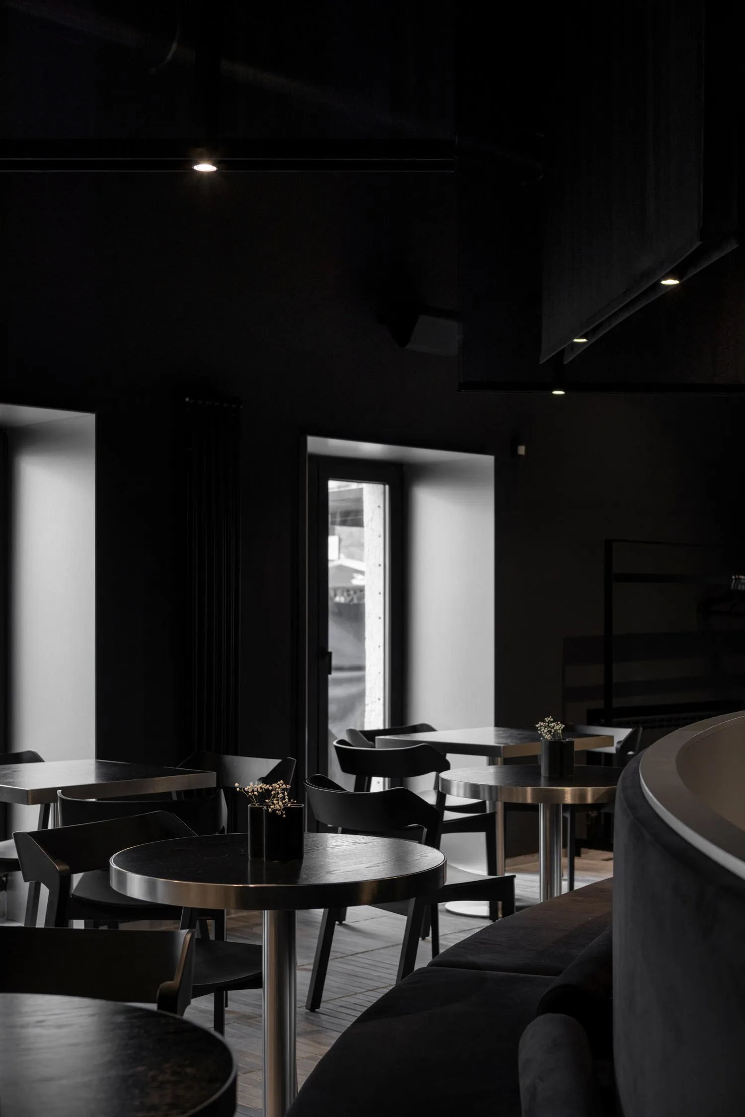 Modern restaurant interior with black walls, dining tables, and chairs, creating a stylish and inviting atmosphere