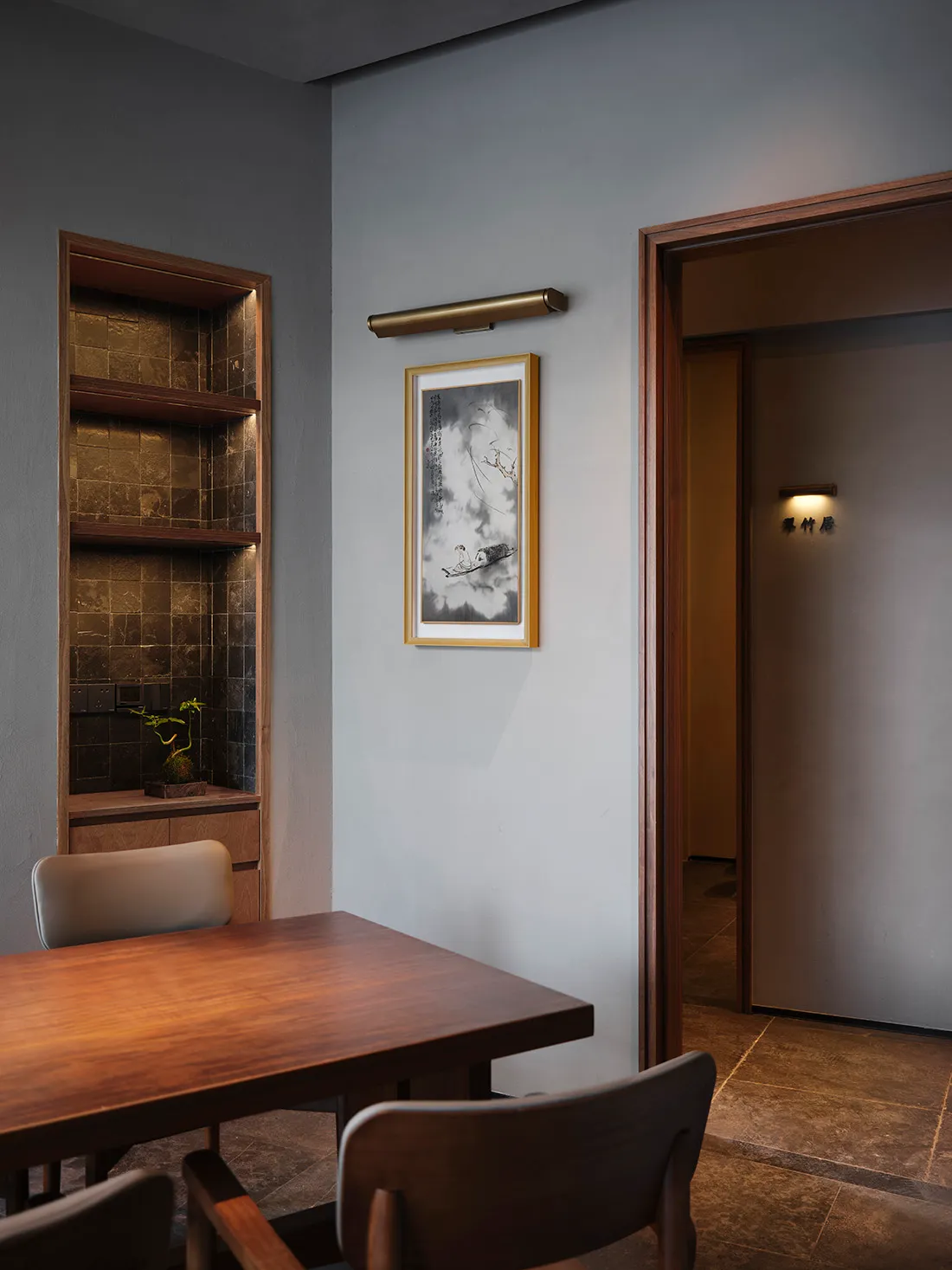 Modern living area with a wooden dining table, chairs, and a doorway leading to another part of the house