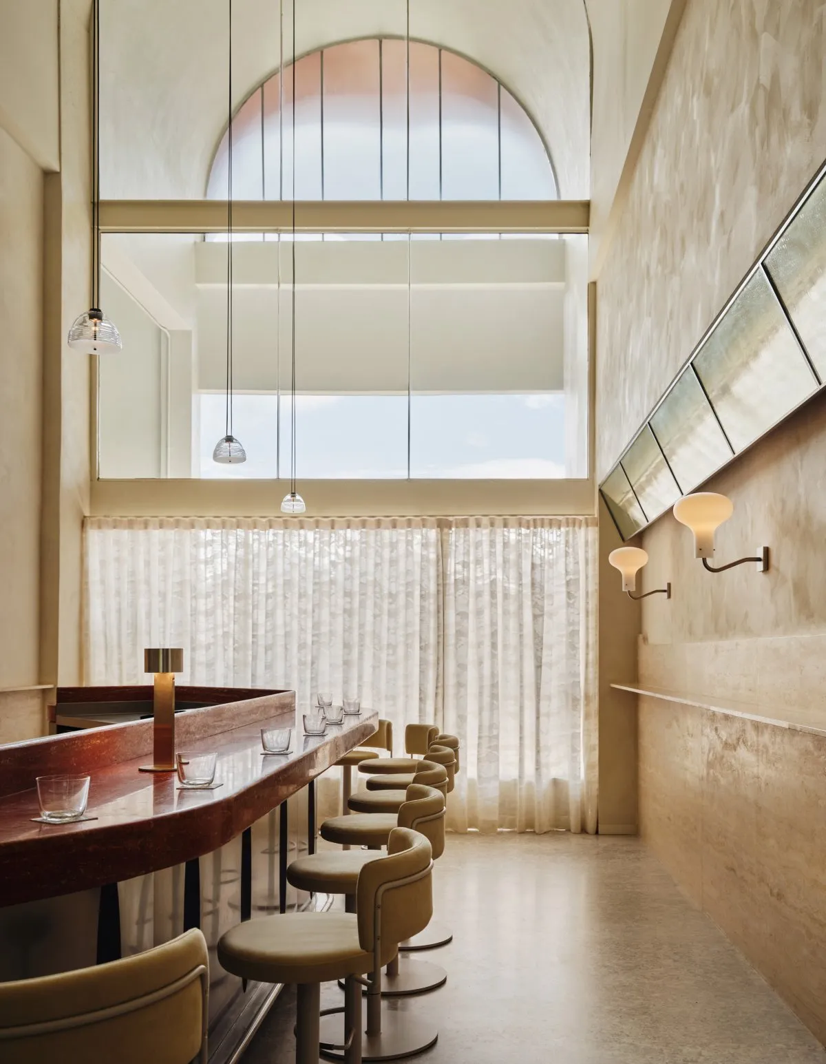 Spacious modern restaurant interior with a long wooden bar counter and several chairs, creating a welcoming atmosphere