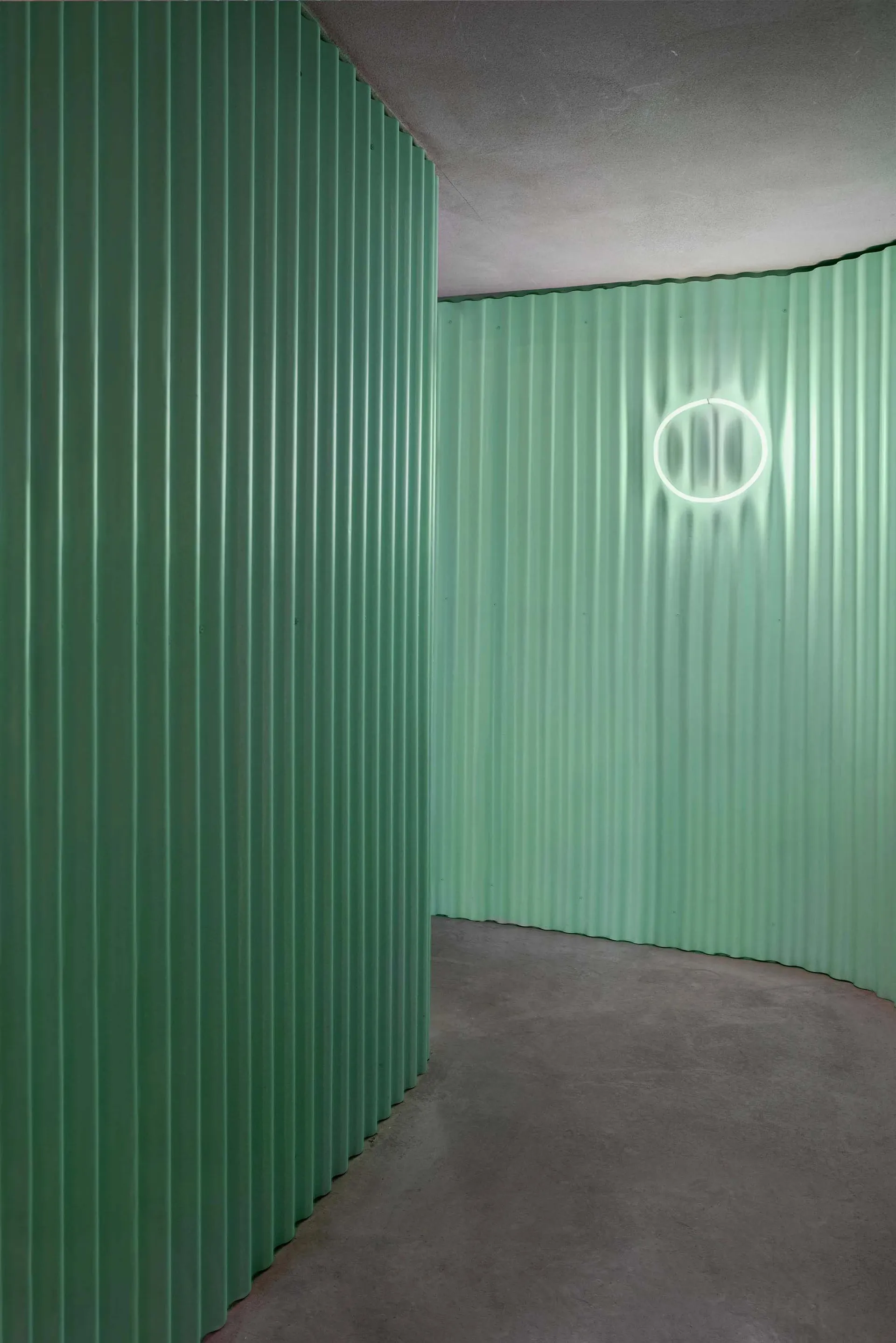 綠色金屬牆面與中性色調牆面交織的暗色空間，營造神秘氛圍