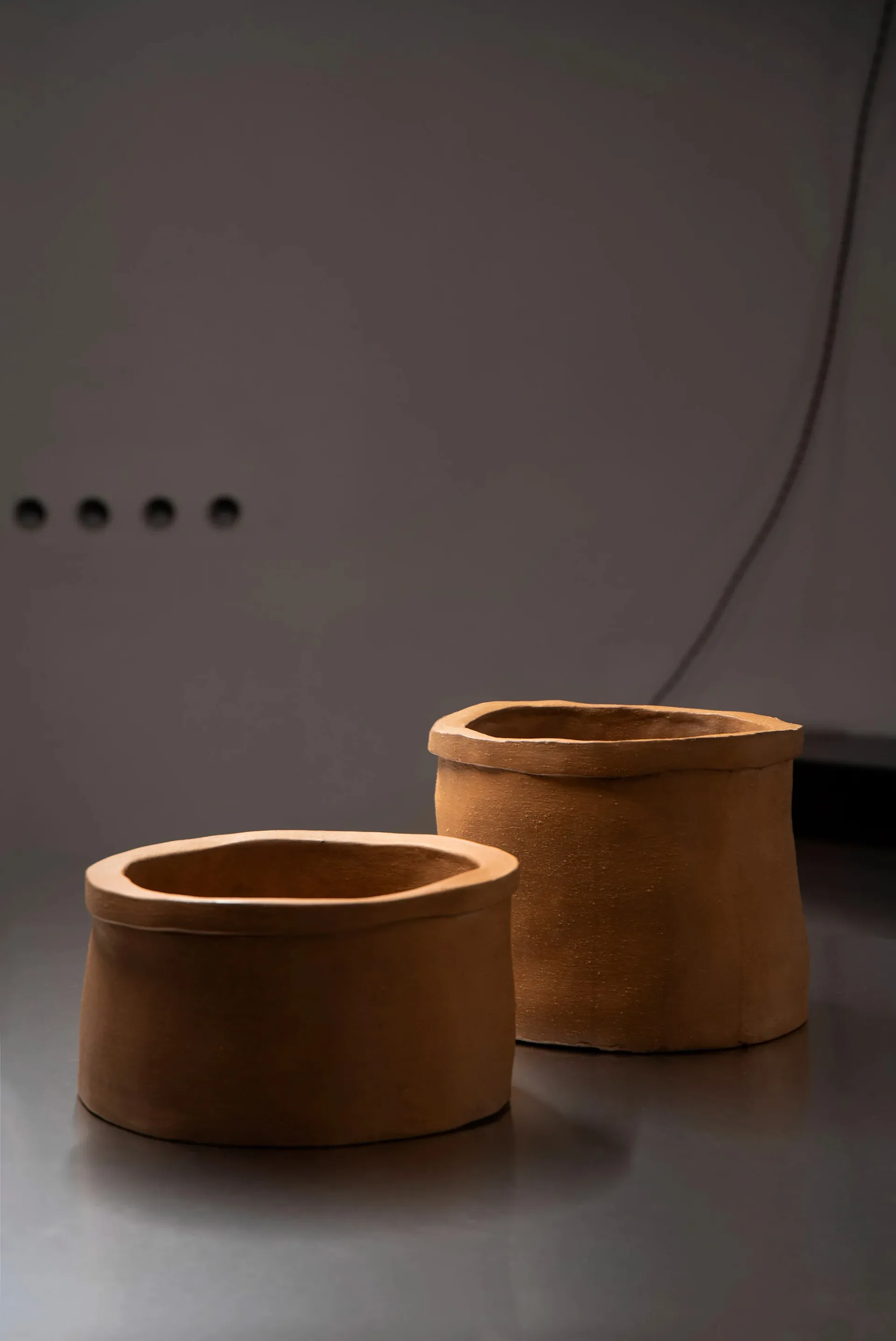 Two brown clay vases on a table in a dimly lit room create a calm and serene atmosphere