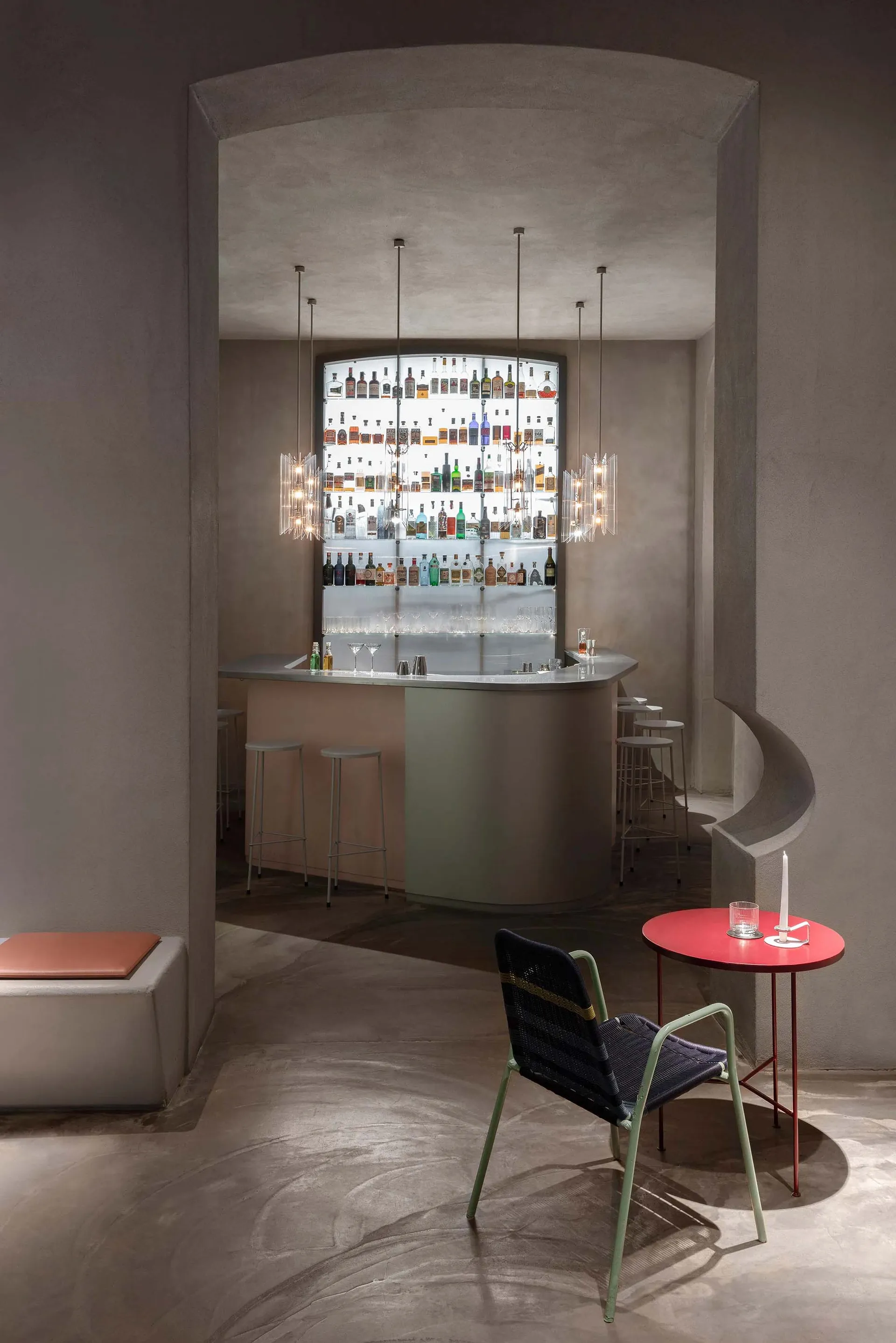 A stylish bar area with a silver counter, wine rack, chairs, and dining tables, creating a welcoming space for socializing and dining